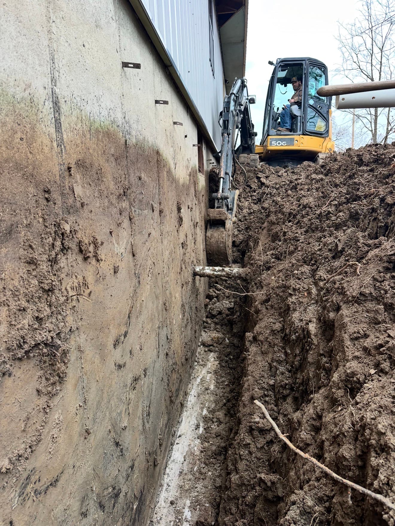 Deep trench excavation next to a metal building — mini excavator rental in north central Missouri